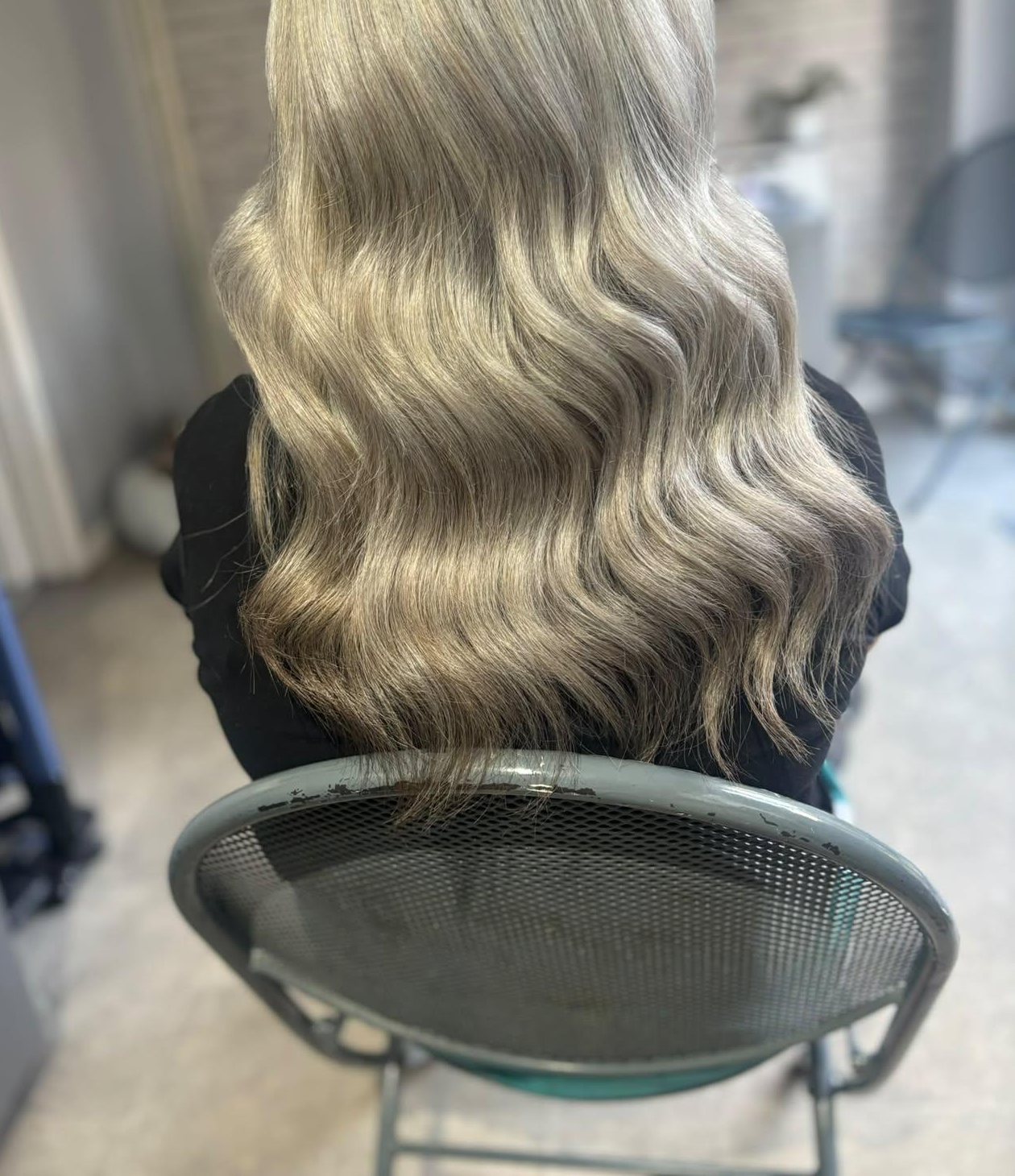 Long ash blonde hair styled in soft waves, seen from behind