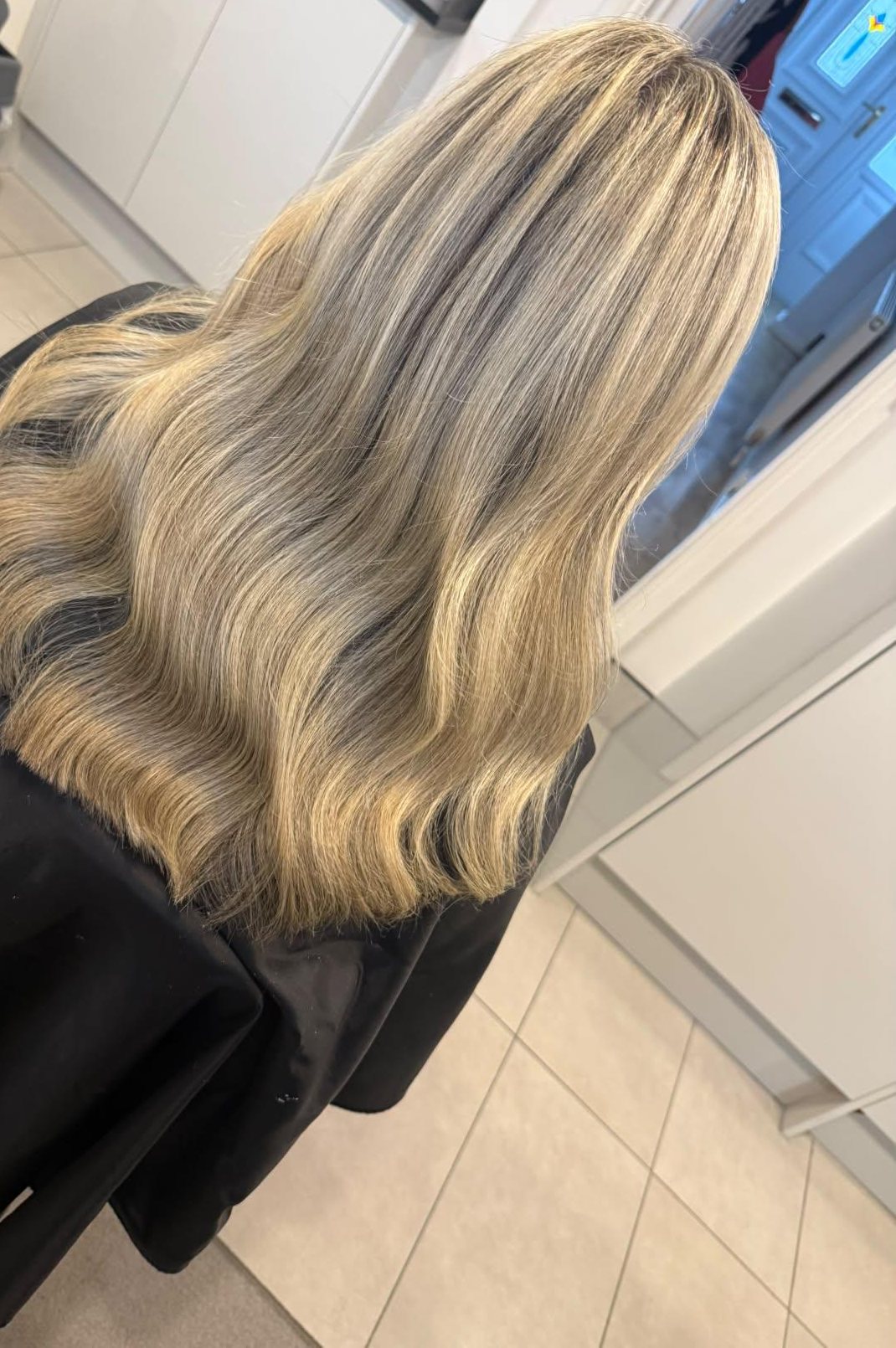 Warm blonde hair with a soft darker root, seen from behind