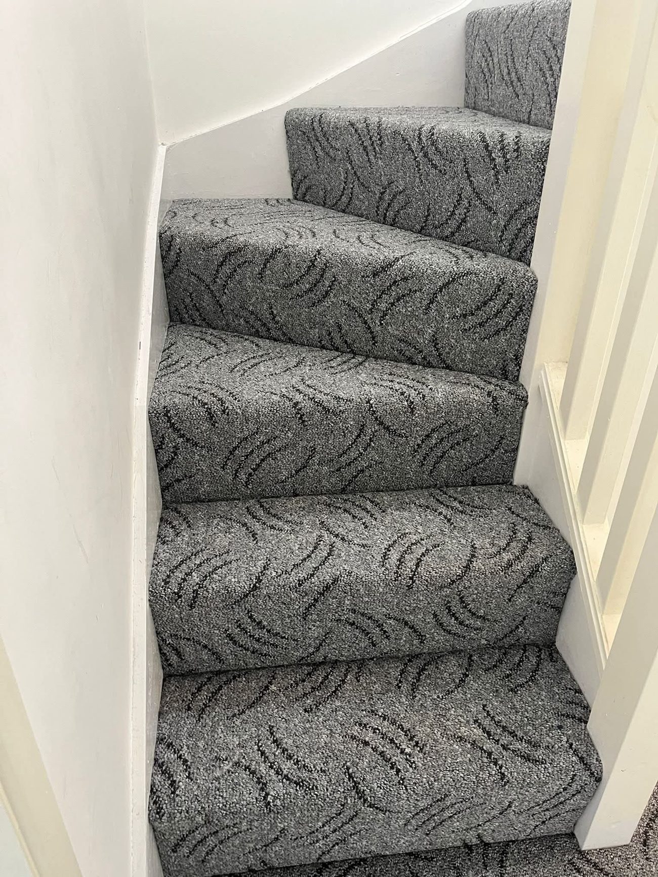 Patterned grey carpet fitted up a narrow staircase